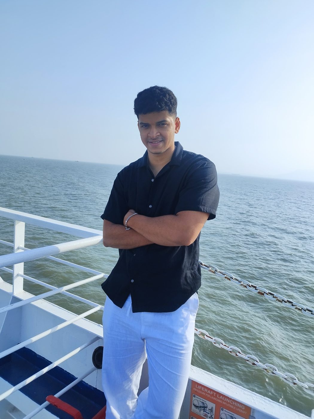 Himanshu on a boat, arms folded, the sea behind him